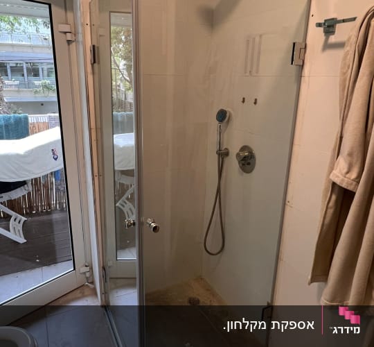 מקלחון פינתי מזכוכית שקופה עם דלת ציר בחדר רחצה
